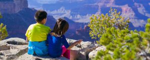 two siblings sitting at grand canyon